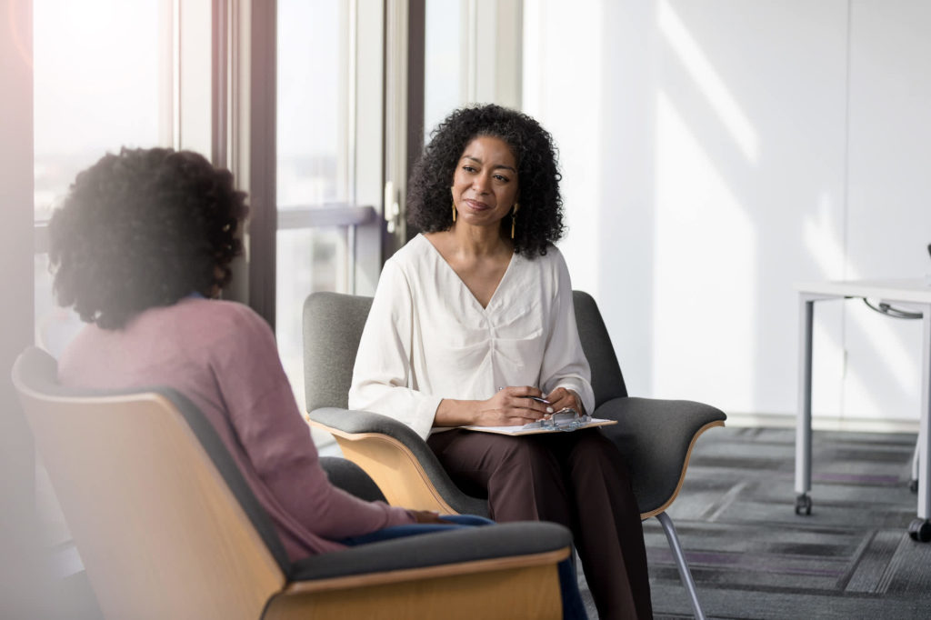 Mental health billing blog: a therapist talking with a client in a bright office