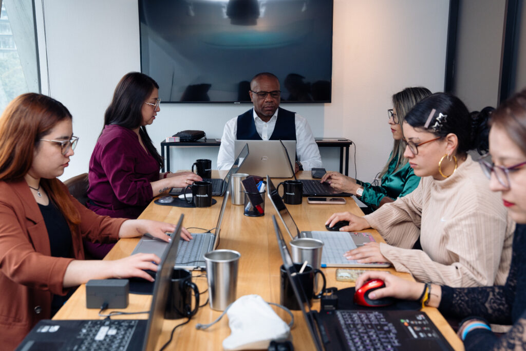 Private Practice Management for Therapists and Psychiatrists 1 Michael Williams leading a private practice management meeting with a team seated around a conference table with laptops